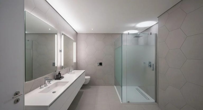 Modern bathroom design featuring a sleek vanity with dual sinks, illuminated mirrors, and a glass shower enclosure with hexagonal tile accents, reflecting contemporary renovation styles relevant to Duluth bathroom remodeling.